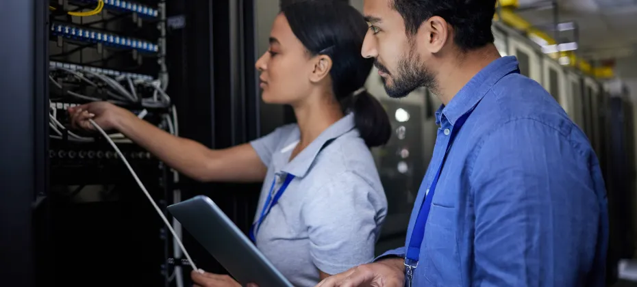Deux personnels en train de réaliser la maintenance d'un onduleur dans un data center